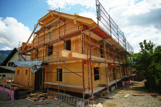 Wooden house under construction with scaffold rig