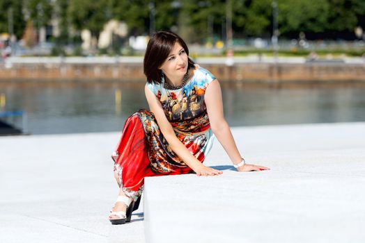 Brunette girl model in dress posing on exterior set