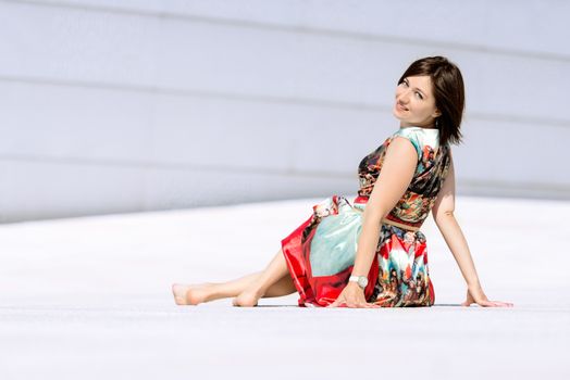 Brunette girl model in dress posing on exterior set