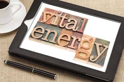 vital energy typography - text in letterpress wood type blocks on a digital tablet with cup of coffee