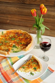 Cheese tart with red wine and red tulips on wooden background vertical