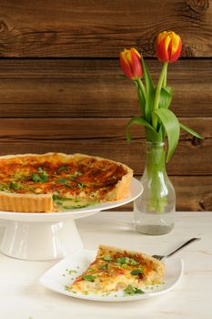 Cheese tart with red wine and red tulips on wooden background vertical