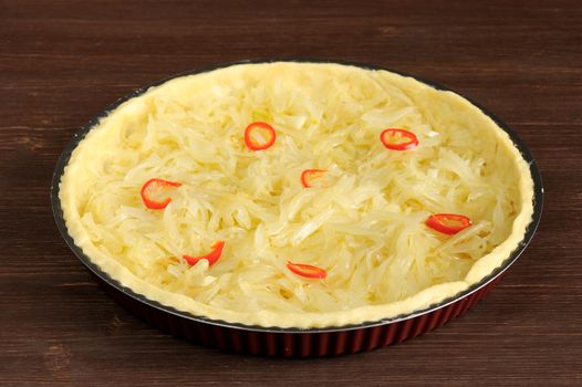 Open onion pie with chili on wooden background closeup