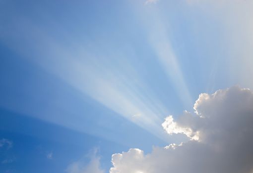 Sunrays passing through clouds and blue sky
