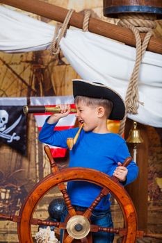 Cute little boy wearing pirate costume on the deck of a ship