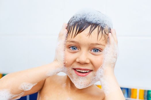 Close-up portrait of cute little boy in bathroom with foam
