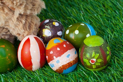 Rabbit, sit on green grass and group of colorful eggs are behind, can use as background for happy easter festival