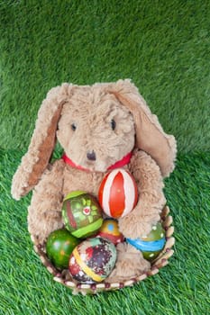 Rabbit, sit and holding colorful eggs in basket on grass for happy easter festival, top view