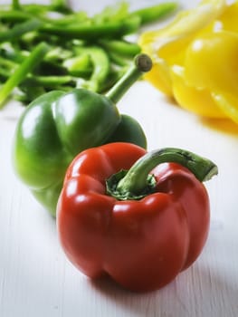 Raw green and red peppers on white table