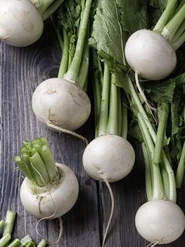White turnips on wodden table and green leaves