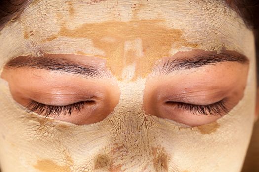 Close up of beautiful indian woman with closed eyes and having face mask of calamine