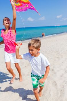 Summer vacation - Cute boy and girl flying kite beach outdoor.