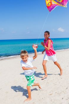 Summer vacation - Cute boy and girl flying kite beach outdoor.