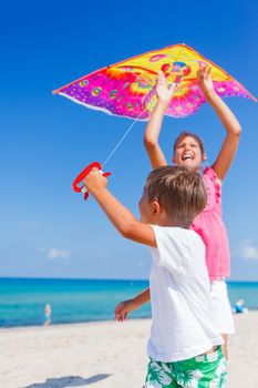 Summer vacation - Cute boy and girl flying kite beach outdoor.