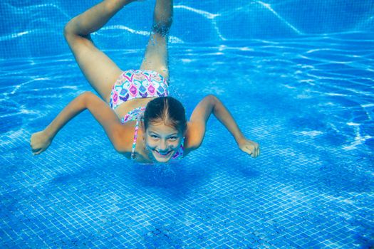 Underwater happy cute girl in swimming pool