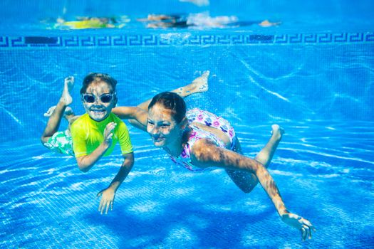 Underwater happy cute girl and boy in swimming pool