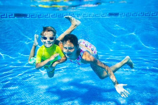 Underwater happy cute girl and boy in swimming pool