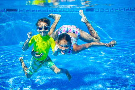 Underwater happy cute girl and boy in swimming pool