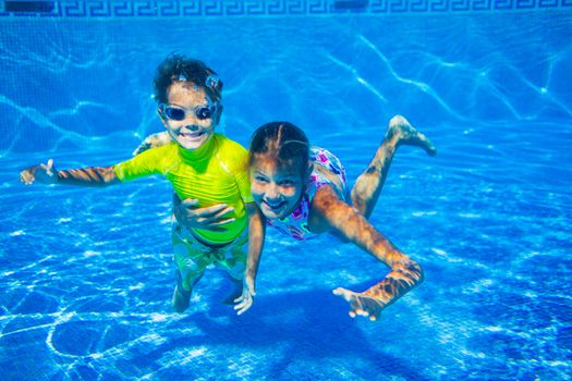 Underwater happy cute girl and boy in swimming pool