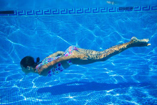 Underwater happy cute girl in swimming pool