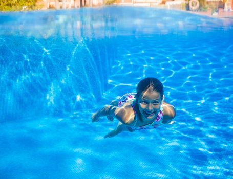 Underwater happy cute girl in swimming pool