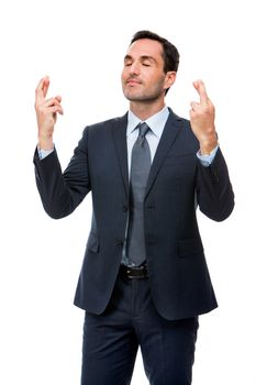 Half length portrait of a businessman with eyes closed and fingers crossed