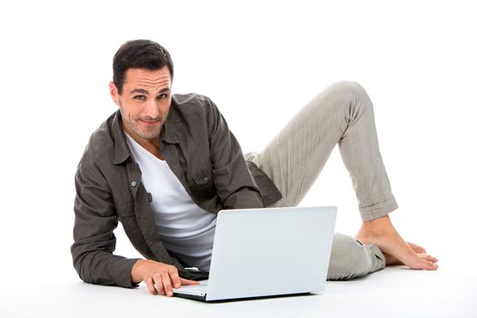 Man laying on the floor, smiling at camera and working with his laptop