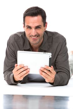 Man laying on the floor, smiling at camera and holding his digital tablet with both hands