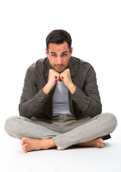 Thoughtful man sitted on the floor, looking at camera, with the hands under his chin