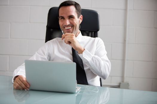 Half length portrait of a male businessman with laptop computer talking with earphones