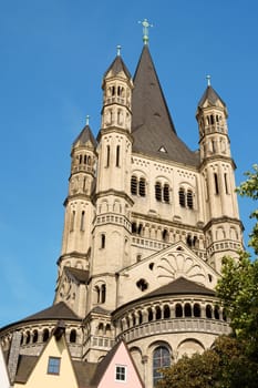 The massive tower of Great Saint Martin Church and ancient colored houses in Cologne, along river Rhine.