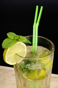 Close-up of a Mojito cocktail with two straws over black background