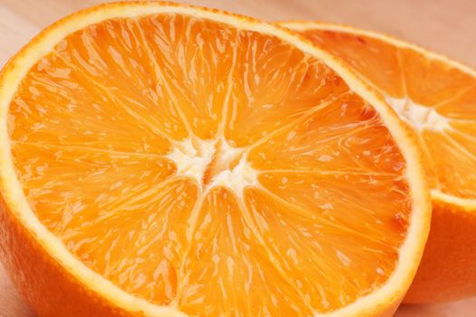 Close-up of an orange cut into two halves over a wooden cutting board