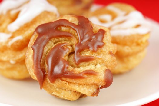 Zeppole di San Giuseppe or St. Joseph's Day Cream Puffs, are south italian deep fried cakes, filled with custard and frosted. Isolated on red.