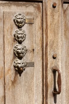 Old wooden door with bronze lion head shaped door bells