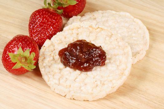 Rice cakes with jam and fresh strawberries over a wooden background. Concept for healthy eating.