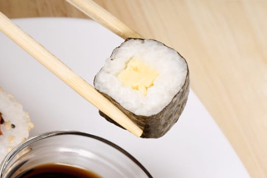 Eating maki sushi roll with wooden chopsticks. Selective focus.