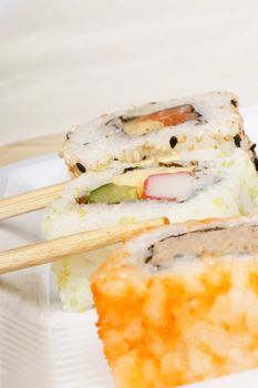 Close-up of three sushi rolls with chopsticks and copyspace. Shallow DOF, selective focus on central roll. 