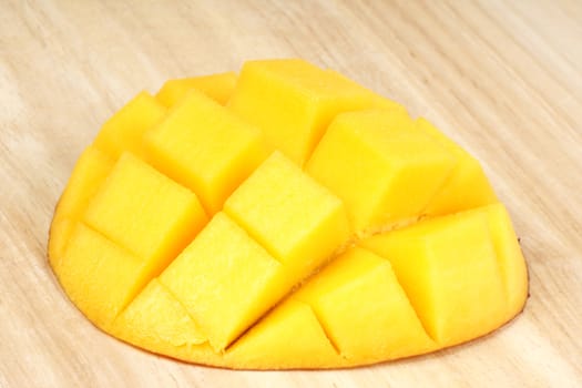 Close-up of a fresh mango piece over a wooden cutting board. 