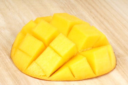 Close-up of a fresh mango piece over a wooden cutting board. 