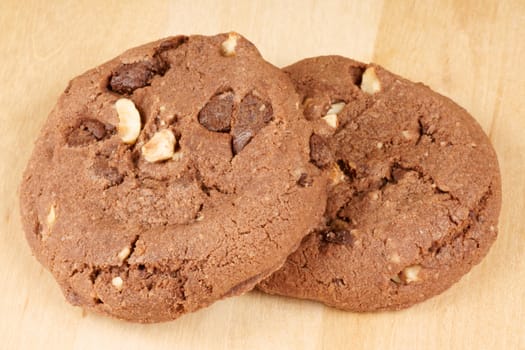 Chocolate cookies with hazelnuts and chocolate chips over a wooden background