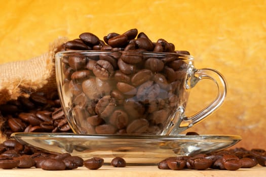 Close-up of a glass cup full of coffee beans over a wooden board