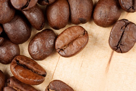 Close-up of some roasted coffee beans over a wooden background with copy space