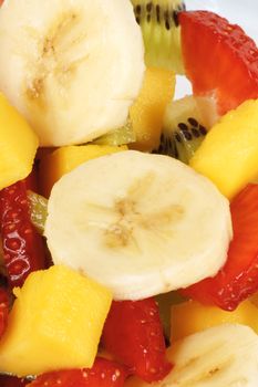 Close-up of a fresh, healthy and colorful fruit salad with banana, mango, kiwi and strawberries.