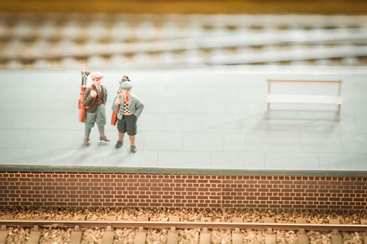 miniature train set figures on a station platform with golf clubs