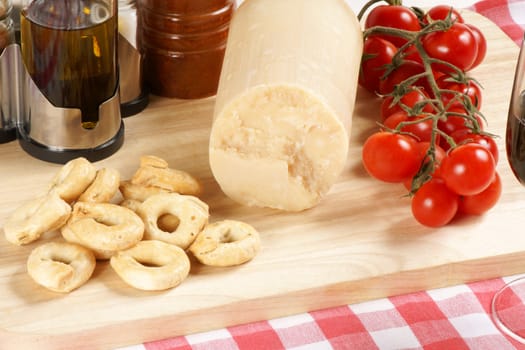 Parmesan cheese, cherry tomatoes and taralli from south Italy served on a wooden cutting board