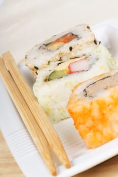 Mixed sushi rolls on a white plate with wooden chopsticks. With copy space. Selective focus.