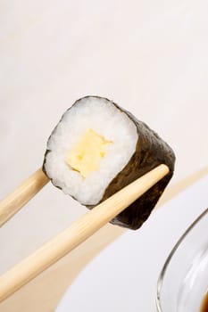 Wooden chopsticks holding a piece of sushi. With copy space. Selective focus.