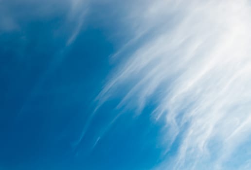 Cloud ad space background. Flighty cirrus clouds covering half the image, the other half is blue.
