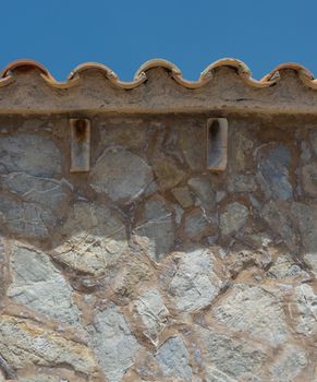 House detail - wall of natural stone and tiled terracotta roof. Typical for Mallorca, Balearic islands, Spain.